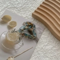 Close-up of a large marbled acetate hair claw clip on a stylish lifestyle background - Marble Gray