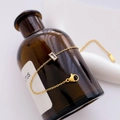 Detail of gold titanium chain bracelet with a square zircon wrapped on a brown glass bottle - Gold Rectangular Zirconia (Bracelet)