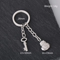 Llavero de acero inoxidable con dije de bolsa de la suerte y llave sobre fondo oscuro - Bolsa de Suerte y Llave / Plateado
