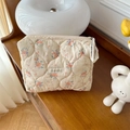 Gros plan détaillé d'une trousse de maquillage matelassée fleurie sur une table en bois - Floral Orange