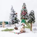 Nahaufnahme von Holz-Wichtel-Anhängern mit Perlen an einem verschneiten Weihnachtsbaum - Zwerg mit grünem Hut