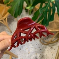 Detailed view of a large deep red hair claw clip with a glossy finish and hollow design - Butterfly Phoenix Tail / Ancorra Red