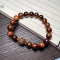 Deep brown rosewood bead bracelet with carved cylinder bead and gold metal spacers - 10mm Bead With Carved Fret Pattern