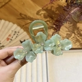Detail view of sage green floral hair claw with crystals on a vintage background - Green