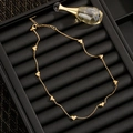Minimalistische Goldkette mit acht Zirkonia-Herzanhängern auf einem schwarzen Tablett - 81013 Zirkon Herz Halskette / Gold