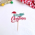 Detailed view of Merry Christmas cake topper with red hat and green banner on festive table - Style F Merry Christmas