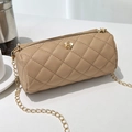 Camel cylinder crossbody bag with diamond quilting and gold flower detail on white table - Khaki