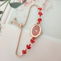 Macro view of adjustable rose gold leaf watch featuring red crystals and quartz dial - Red