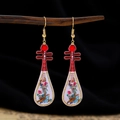 Detailed view of red and white lute-shaped earrings with floral patterns and gold hooks - Red Head White Pipa