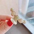 Close-up of golden claw clip featuring marbled light green and white decorative spheres - Light Silver-White Marble