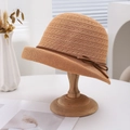 Breathable woven sun hat with side bow detail on a wooden stand for summer sun protection - Rose Gold