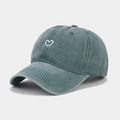 Close-up of heart embroidery on washed dark green cotton baseball cap fabric texture - Green