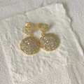 Orecchini dorati a doppio cerchio con pavé di zirconi su carta bianca con texture - Base Dorata Strass Bianchi