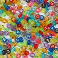 Macro shot of colorful glitter acrylic alphabet beads for DIY jewelry and crafts - Transparent Multicolor with Glitter and Silver Letters