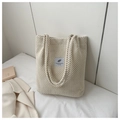 Detail of cream corduroy tote bag featuring a minimalist patch and woven texture finish - White