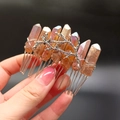 Nahaufnahme des Haarkamms mit rot-orangefarbenen Kristallen und silbernem Ast-Design - Milchteefarbener Kristall + Zweig