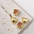 Dettagli macro di ciondoli melograno placcati oro 14K con zirconi rossi su base di pietra - Oro