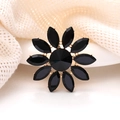 Gros plan d'une broche fleur dorée avec cristaux noirs sur tissu en résille beige - Noir