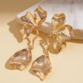 Detailed view of golden flower earrings with textured petals on marble surface - Stainless Steel Post - Gold
