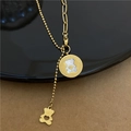 Detailed macro view of golden bear pendant with white shell inlay and asymmetric chain - Round Bear