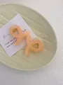 Detail of two beige acrylic hair claws with gold springs in a ceramic tray - Mini Butterfly Clip X-Shaped (Approx. 4cm) / Translucent Bright Orange