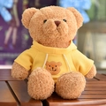 Cute teddy bear plush toy wearing a yellow hoodie sitting on a wooden table - Hoodie Bear / 30 cm / Yellow