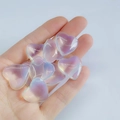 Hand holding polished 2cm heart-shaped iridescent colorful crystals for decoration - Clear