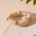 Detail eines Acryl-Armbands im Bambusstil mit Marmormuster und goldenen Metallperlen - Gebrochenes Weiß