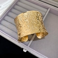Detailansicht eines breiten goldenen Armreifs mit geprägten Blumen- und Paisleymustern - Gold