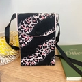 Detalle de bolso de punto negro con estampado de leopardo rosa sobre madera - Cebra Negro