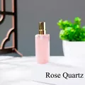 Edle Parfüm-Sprühflasche aus Rosenquarz mit goldener Kappe auf weißem Displayblock - Rosenquarz