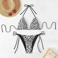 Flat lay of a leopard print bikini set with a straw hat and sunglasses on stone surface - White & Black Leopard Print