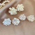 Vista dettagliata di tre paia di eleganti orecchini a lobo a fiore bianco su sfondo di seta - Set da 6 pezzi / 2# Perno per orecchino in argento - Bianco