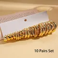 Set mit 10 Paar goldenen geometrischen Creolen auf weißem Karton präsentiert - Stahlnadel - Gold - 20-teiliges Set