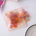 Dettaglio di elastici colorati per capelli in una simpatica bustina con zip a orsetto - Colori Scuri