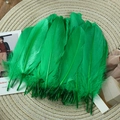 Close-up of vibrant emerald green goose feathers on a woven mat for DIY crafts and decor - Stiff Grass Green (50Pcs)