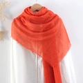 Solid orange pleated cotton linen scarf with frayed edges displayed on a hanger - Orange