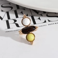 Detailed shot of retro gold ring with marble stone and black mineral on a magazine - Lemon Jade + White Turquoise