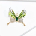 Macro detail of butterfly brooch with green gems and glittering wings on gold metal - Glitter Green Butterfly