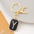 Macro shot of letter Y keychain with clear rhinestones on black enamel metal plate - Letter Y
