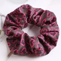 Dettaglio di uno scrunchie in raso con cuori rosa su sfondo di tessuto scuro - Cuore Magenta