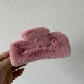 Detailed view of a soft pink faux fur hair claw clip held against a white textured wall - Deep Pink