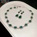 Macro shot of vintage silver-plated jewelry set with emerald drop stones on ceramic tray - Green 2-Piece Set / Green