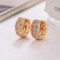 Elegante 18K Gold Huggie Ohrringe mit Cubic Zirkonia auf einer Steinfläche - Gold