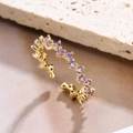 Detail of 18K gold plated wavy ring with round purple zircon stones on stone background - Adjustable Open / Purple Zirconia