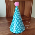 Detalle de gorro de fiesta azul cielo con rombos blancos y un pompón rosa superior - Talla única / Sombrero de cumpleaños de rejilla azul