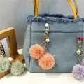 Detail of colorful faux fur pom-pom bag charms with gold chains and pearl accents - Orange Red