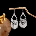 Detailed view of silver ethnic leaf tassel earrings hanging on a natural wooden branch - Silver Hollow Water Drop Leaf Tassel Style (E2873-22)