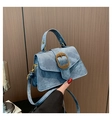 Detail of blue denim fabric crossbody bag with vintage gold buckle on wooden background - Blue