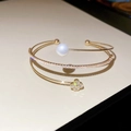 Detail of a three-layer gold open bangle featuring a pearl and sparkling clover motif - Gold-Triple Layer Clover (HB4665)